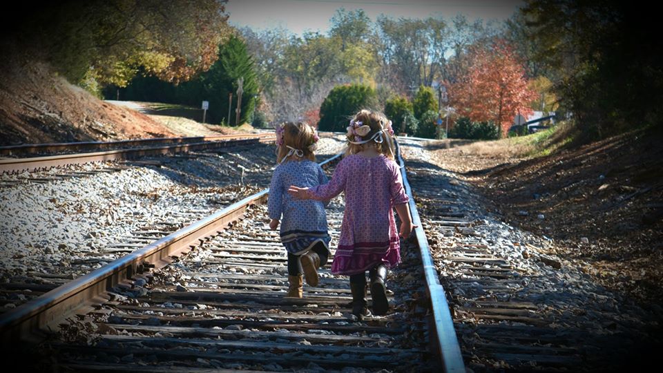 twin girls running down a railroad - building imagination