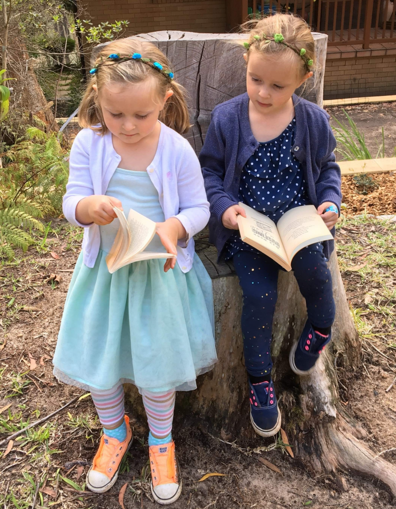 2 girls reading on a log