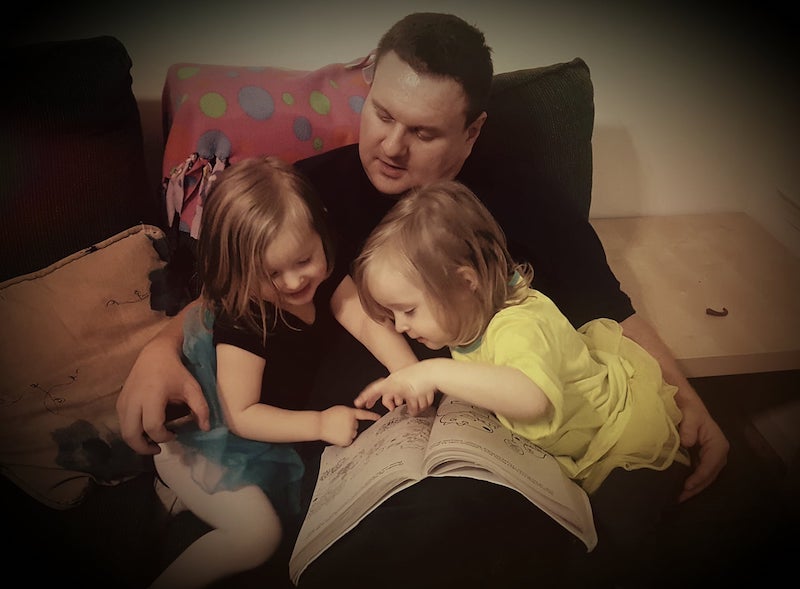 father and twin girls reading