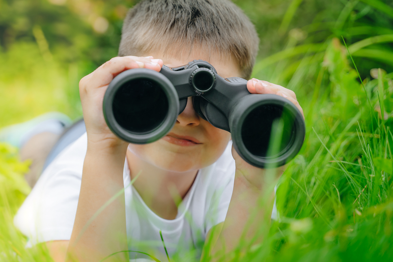 child in grass with binoculars