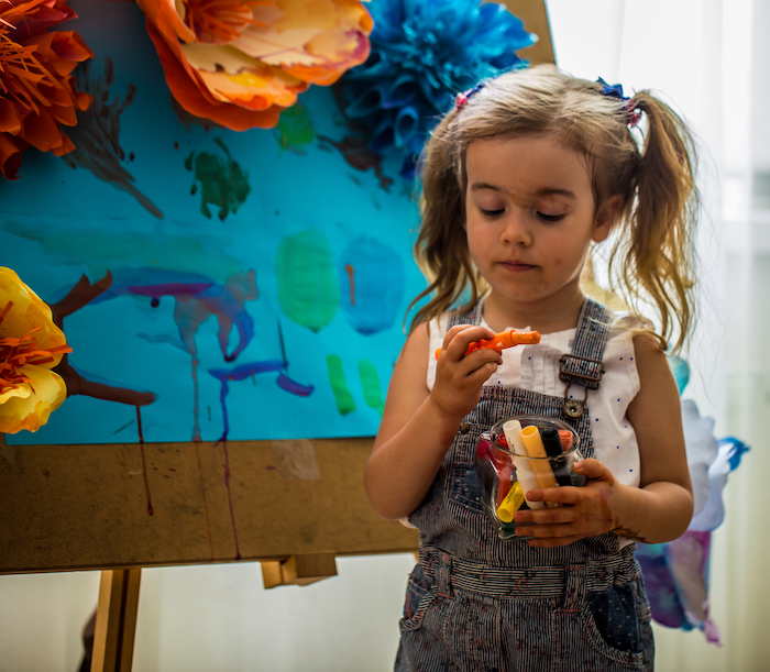 the little girl painting at the easel
