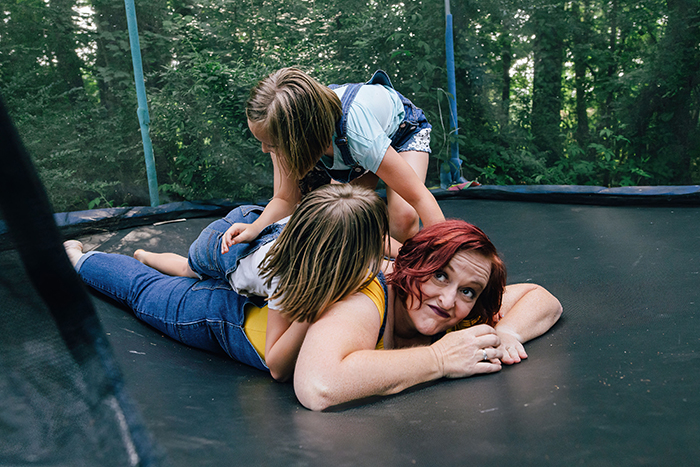 mother playing on trampoline with two little girls